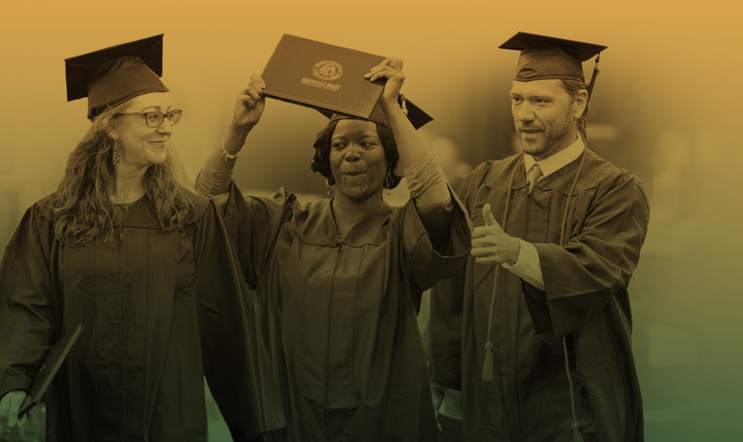 White male, black female and white female in graduation hats and gowns celebrating